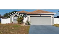 Charming single-story home featuring a well-manicured lawn, arched window, and two-car garage at 212 Ashford Dr, Davenport, FL 33837