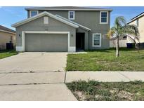 Two-story home featuring an attached two-car garage and a young palm tree in the front yard at 235 Hibiscus St, Winter Haven, FL 33881