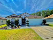 Charming single-story home features a well-manicured lawn and flower beds under a bright blue sky at 2376 Flamingo Lakes Dr, Kissimmee, FL 34743