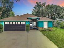 Charming turquoise home featuring a well-kept lawn, a dark grey garage door, and a cozy front porch at 2545 El Portal Ave, Sanford, FL 32773