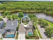 Stunning aerial view of waterfront home with screened-in pool and lush greenery at 3201 Glenmere Way, Orlando, FL 32828