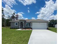 Beautiful single-story home with a well-manicured lawn and a two-car garage on a sunny day at 3498 Sw 131St Place Rd, Ocala, FL 34473