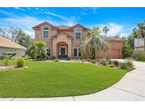 Charming two-story brick home featuring a well-manicured lawn and mature landscaping at 383 Remington Dr, Oviedo, FL 32765