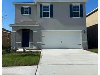 Two-story home featuring blue shutters, a two-car garage, and a well-manicured lawn at 4908 Kaia Ave, Winter Haven, FL 33884