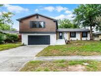 Two-story home with brown siding, white painted brick, an attached garage, and freshly landscaped yard at 7085 Willowwood St, Orlando, FL 32818