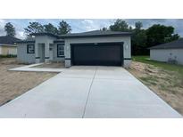 Contemporary single-Gathering home featuring a gray color scheme, black garage door and complementing landscaping at 7382 Sw 129Th Ln, Ocala, FL 34473