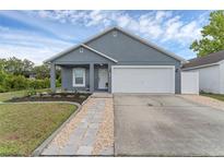 Charming single-story home with gray stucco exterior, well-manicured lawn and attached white two car garage at 7998 Harbor Bend Cir, Orlando, FL 32822