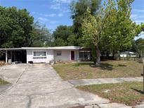 Charming single-story home with a red front door and a mature tree in the front yard at 128 N Sunland Dr, Sanford, FL 32773