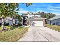 Charming two-story home featuring a spacious driveway, manicured lawn, and attached two-car garage at 1428 Casterton Cir, Davenport, FL 33897
