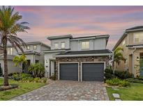 Two-story home featuring stone accents, a brick driveway, lush landscaping, and a two-car garage at 15702 Vetta Dr, Bella Collina, FL 34756