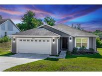 Charming single-story home with gray exterior, well-manicured lawn, and two-car garage at 1857 E Cooper Dr, Deltona, FL 32725