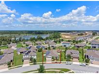 Beautiful aerial view of a single-Gathering home with a well-manicured lawn, solar panels, and nearby pond in a vibrant community at 209 Luxmore Rd, Groveland, FL 34736