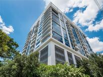 Modern high-rise building with glass balconies against a blue sky with bright white clouds at 260 S Osceola Ave # 1207, Orlando, FL 32801