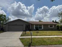 Charming single-story home featuring a well-maintained lawn and an attached two-car garage at 2747 Rose Moss Ln, Orlando, FL 32807