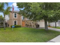 Inviting two-story home with a well-maintained lawn, orange door and lush landscaping at 4927 Fiske Cir, Orlando, FL 32826