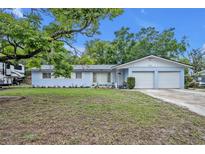 Charming single-story light blue home with an attached two-car garage and mature landscaping in the front yard at 806 Bear Lake Rd, Apopka, FL 32703