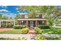 Charming red brick home featuring a screened porch, manicured lawn, and lush landscaping at 900 S Palmetto Ave, Sanford, FL 32771