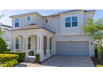 Charming two-story home featuring an inviting front porch with columns and a paved driveway to a two-car garage at 9038 Sunshine Ridge Loop, Kissimmee, FL 34747