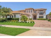 Attractive home featuring a well-maintained lawn, paver driveway, and lush tropical landscaping at 13125 Alderley Dr, Orlando, FL 32832