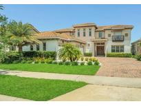 Inviting two-story home featuring lush landscaping, a terracotta tile roof, and a brick paved driveway at 13125 Alderley Dr, Orlando, FL 32832