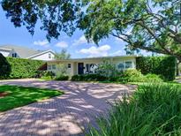 Charming single-story home featuring a brick driveway, manicured lawn, and mature landscaping at 1791 Spruce Ave, Winter Park, FL 32789
