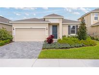 Charming single-Gathering home featuring a two-car garage, gray brick driveway, and inviting front yard landscaping at 2026 Firethorn Loop, Haines City, FL 33844