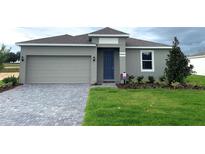 Charming single-story home featuring a gray exterior, manicured lawn, and a convenient two-car garage at 2026 Firethorn Loop, Haines City, FL 33844