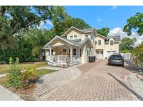 Charming two-story home with a welcoming front porch and brick driveway and lush landscaping at 2223 Amherst Ave, Orlando, FL 32804