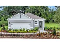Charming single-story home featuring a two-car garage, landscaped yard, and inviting entryway with lush greenery at 3438 Briarwood Grove Dr, Ocoee, FL 34761