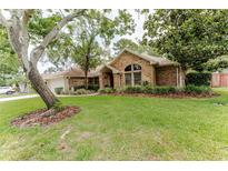 Charming brick home with lush lawn, mature trees, and well-maintained landscaping at 356 Remington Dr, Oviedo, FL 32765