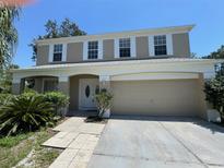 Charming two-story home featuring a covered front porch and a two-car garage with neutral tan paint and clean white trim at 3707 Andover Cay Blvd, Orlando, FL 32825