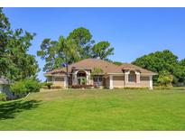 Beautiful one-story home featuring a well-manicured lawn, lush landscaping, and a neutral-colored exterior at 513 N Pine Meadow Dr, Debary, FL 32713