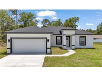 Charming single-story home with a crisp white exterior, black trim, a well-manicured lawn, and a two-car garage at 586 Marion Oaks Trl, Ocala, FL 34473