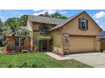 Charming two-story home featuring a well-manicured lawn, arched window and a welcoming brick-accented entrance with flowering trellis at 612 Heron Bay Dr, Orlando, FL 32825