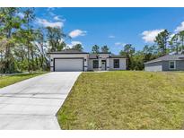 A charming single-story home boasting a well-manicured lawn and a modern white exterior with black trim at 6691 Sw 151Sr Loop, Ocala, FL 34473