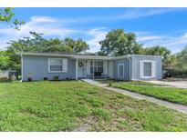 Charming single-story home with light blue siding, green lawn, and welcoming front entrance at 7033 Budapest Way, Orlando, FL 32822
