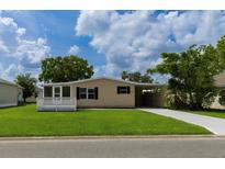 Charming single-story home with well-manicured lawn, carport, and screened in porch perfect for relaxing outdoors at 1220 Dustin Dr, Lady Lake, FL 32159