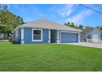 Charming single-story home featuring blue siding, a well-manicured lawn, and an attached two-car garage at 1621 Sunny St, Kissimmee, FL 34741