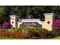 Venetian Bay Villages community sign surrounded by colorful flowers and lush greenery at 2208 San Vittorino Cir # 104, Kissimmee, FL 34741