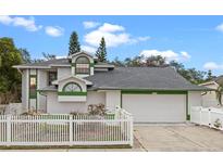 Charming two-story home featuring a well-manicured lawn and white picket fence, complemented by an attached two-car garage at 4527 Sandhurst Dr, Orlando, FL 32817