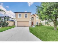 Two-story home featuring neutral siding, manicured lawn, mature trees and an attached two-car garage at 510 Lobelia Dr, Davenport, FL 33837