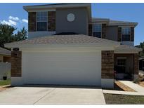 Two-story home featuring a two-car garage and stone facade accents under a clear blue sky at 5107 Ne 122Nd Blvd, Oxford, FL 34484