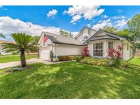 Charming home featuring a landscaped front yard, garden, and attached garage at 544 Remington Oak Dr, Lake Mary, FL 32746