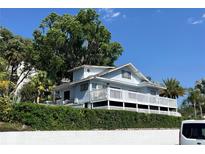Beautiful two-story home with a white wrap around deck, lush trees, and landscaping at 629 Helen St, Mount Dora, FL 32757
