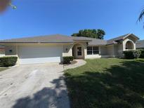Charming single-story home with a well-manicured lawn and a two-car garage, under a clear blue sky at 7507 Sandstone Dr, Orlando, FL 32836