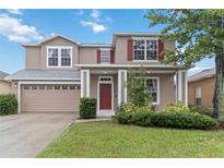 Charming two-story home featuring a red front door, attached garage, and well-maintained landscaping at 7551 Bear Claw Run, Orlando, FL 32825