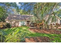 Charming brick home featuring a well-manicured lawn, mature trees, and beautiful landscaping at 828 Timber Court Ct, Apopka, FL 32712