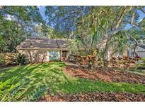 Charming brick home featuring a well-manicured lawn and lush tropical landscaping at 828 Timber Court Ct, Apopka, FL 32712