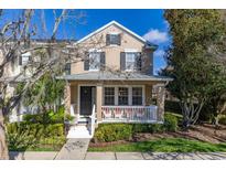 Charming two-story home featuring a cozy front porch, classic shutters, and lush landscaping at 9141 Camden Gardens St, Orlando, FL 32827