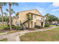 Inviting two-story condo with charming yellow siding, lush landscaping, and convenient exterior staircase access at 1031 S Hiawassee Rd # 2517, Orlando, FL 32835